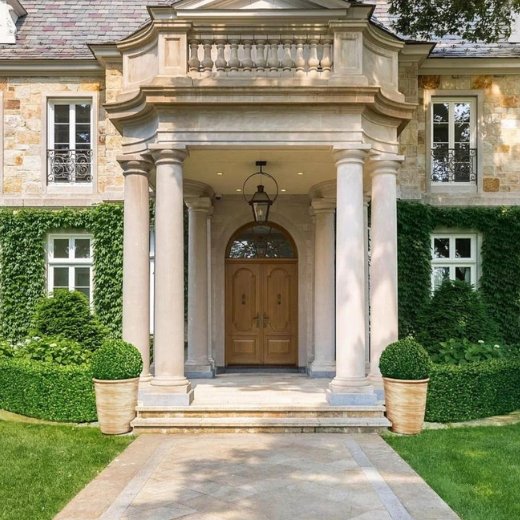 A Victorian style beige painted house front with a walkway and a lawn on both sides.
